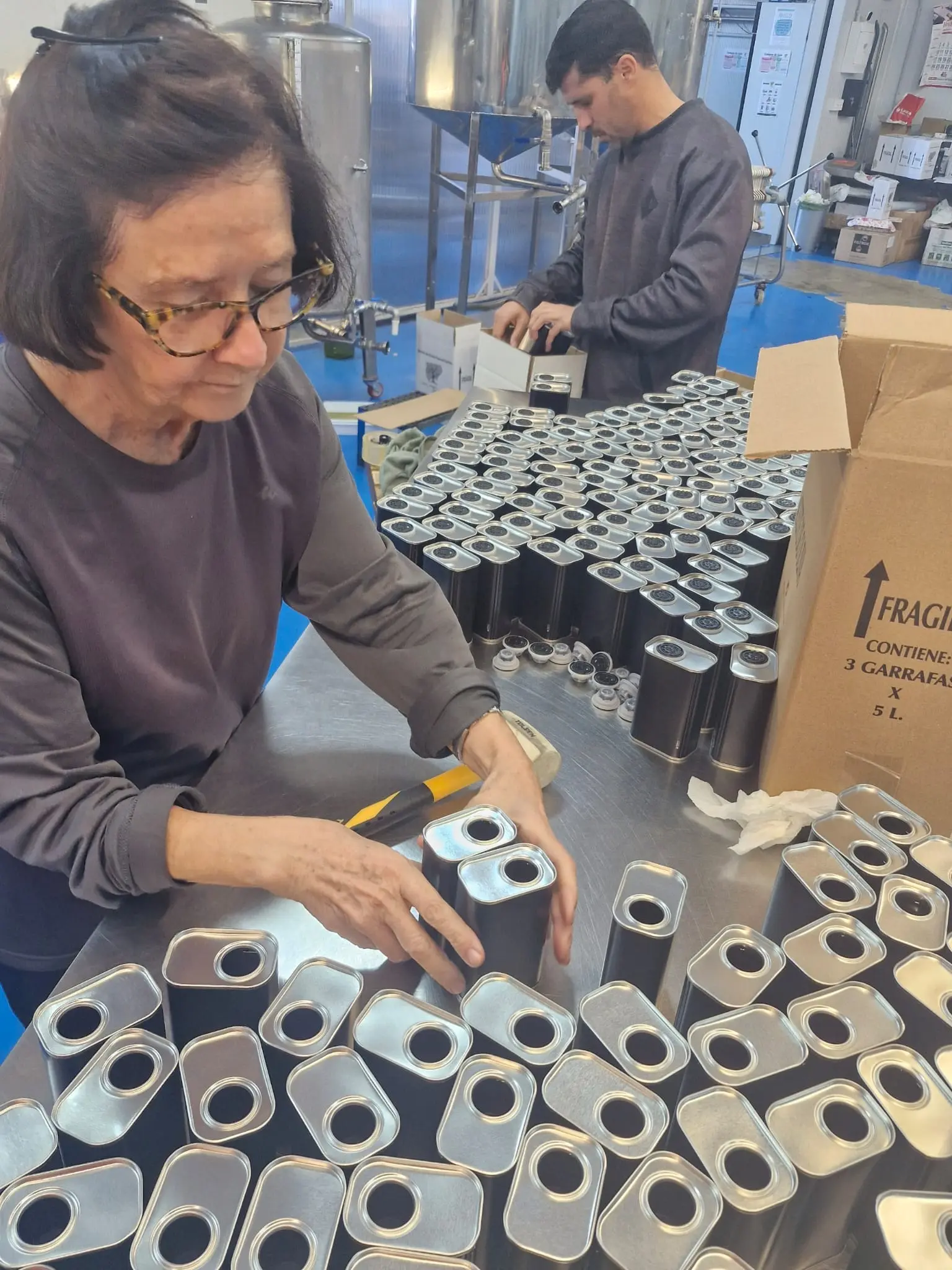 La madre de la familia y Ricardo preparan envases de aceite en la almazara